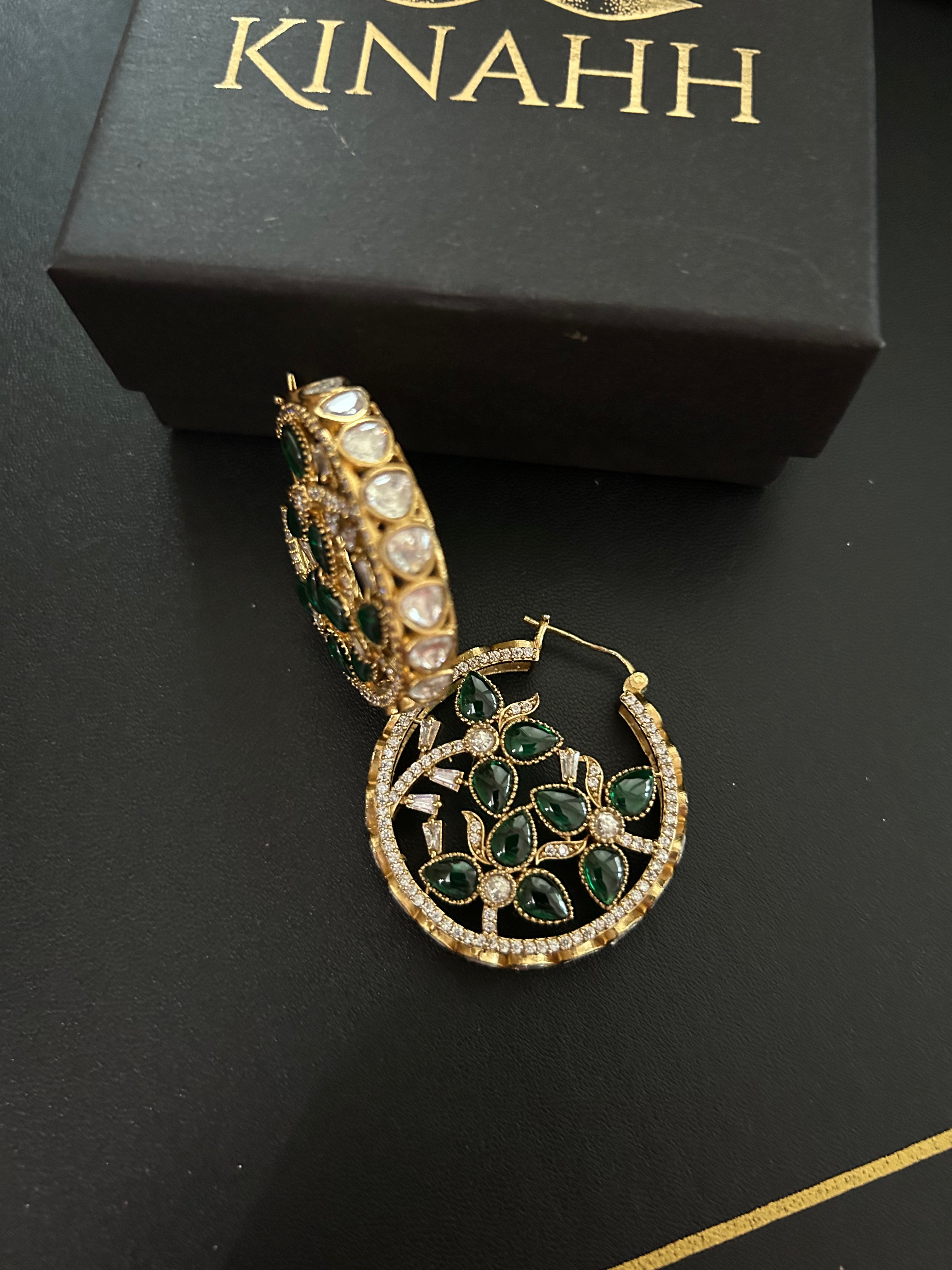 Chaand circular brass hoop earrings with green teardrop stones and moissanite polki, photographed beside a KINAHH box.
