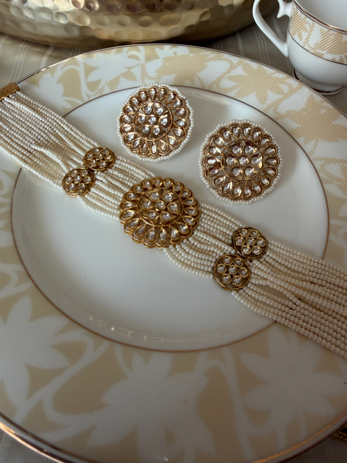 Close view of the Renuka ivory pearl choker with gold-tone clear-stone floral motifs and earrings