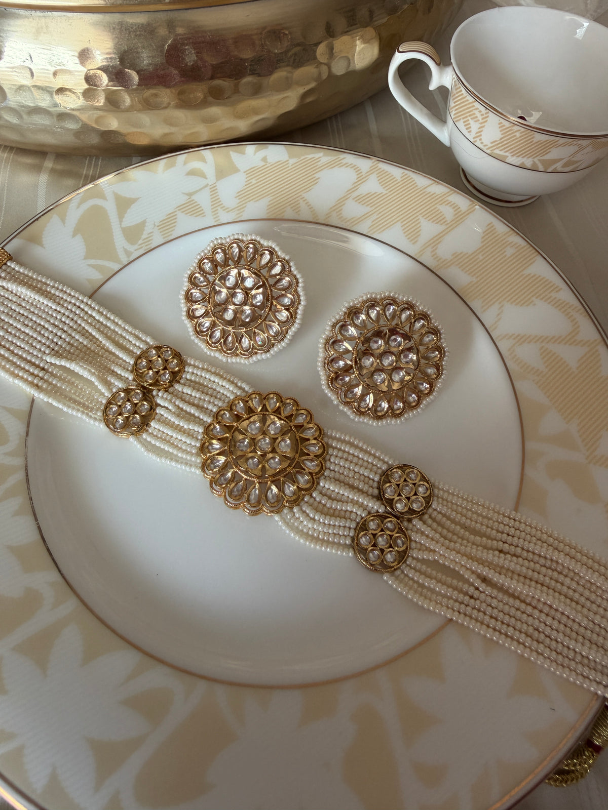 Renuka pearl choker necklace set styled with matching statement stud earrings on a decorative plate