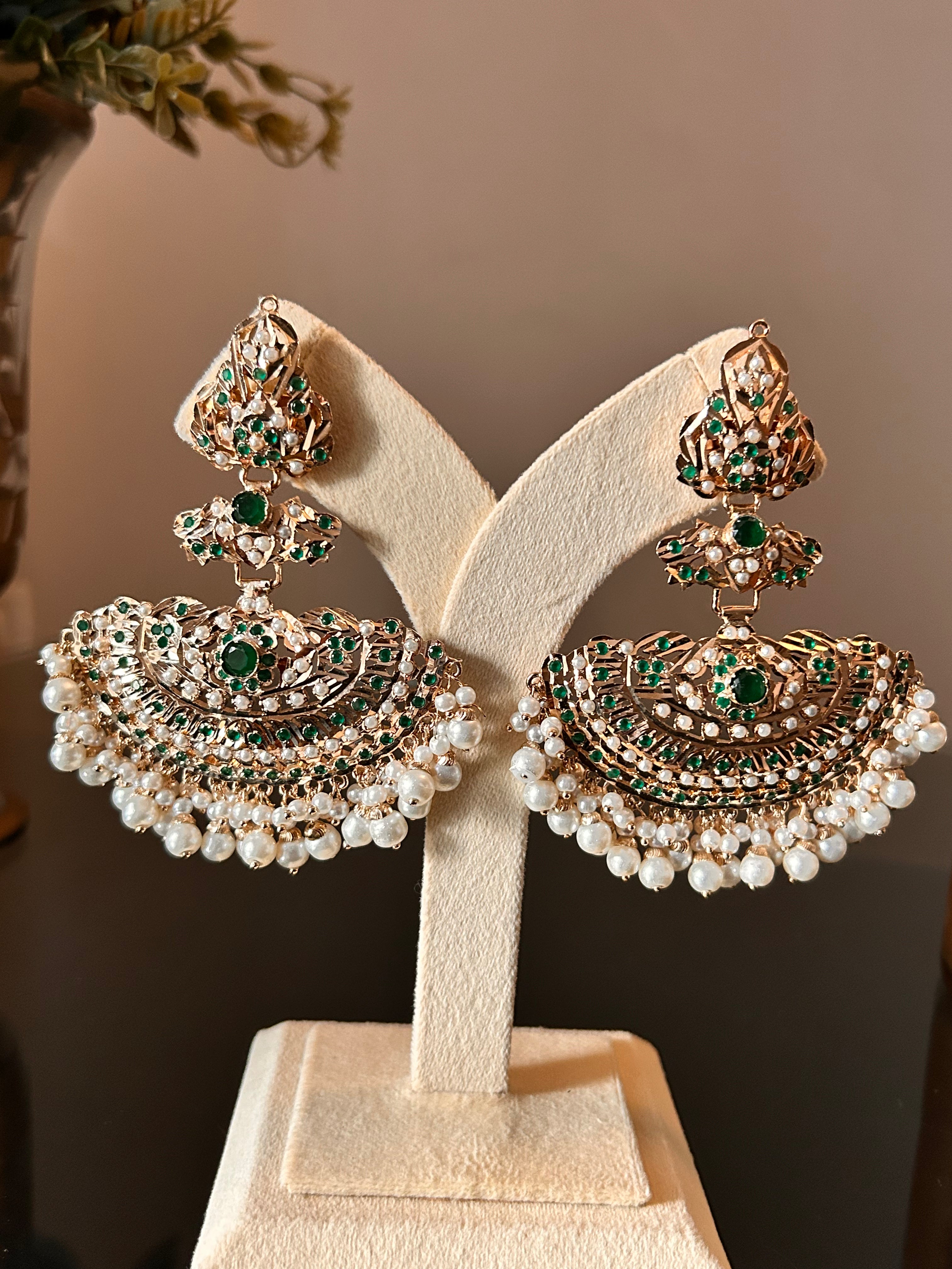 Full-pair view of Khwahish earrings on a cream jewellery stand, showing the long stone-set tops and broad pearl-fringed lower sections.