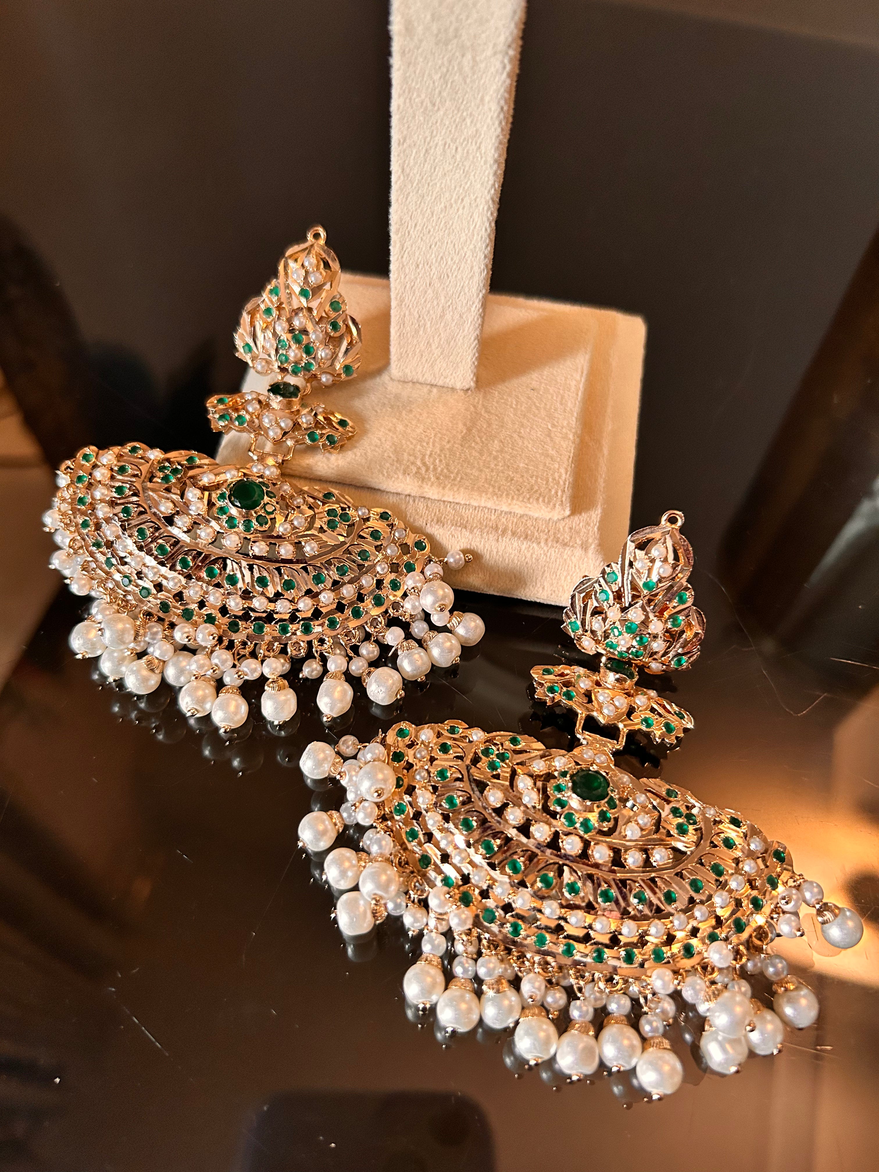 Khwahish earrings resting side by side at the base of a cream display stand, showing the full fan-shaped design and pearl-like drops.