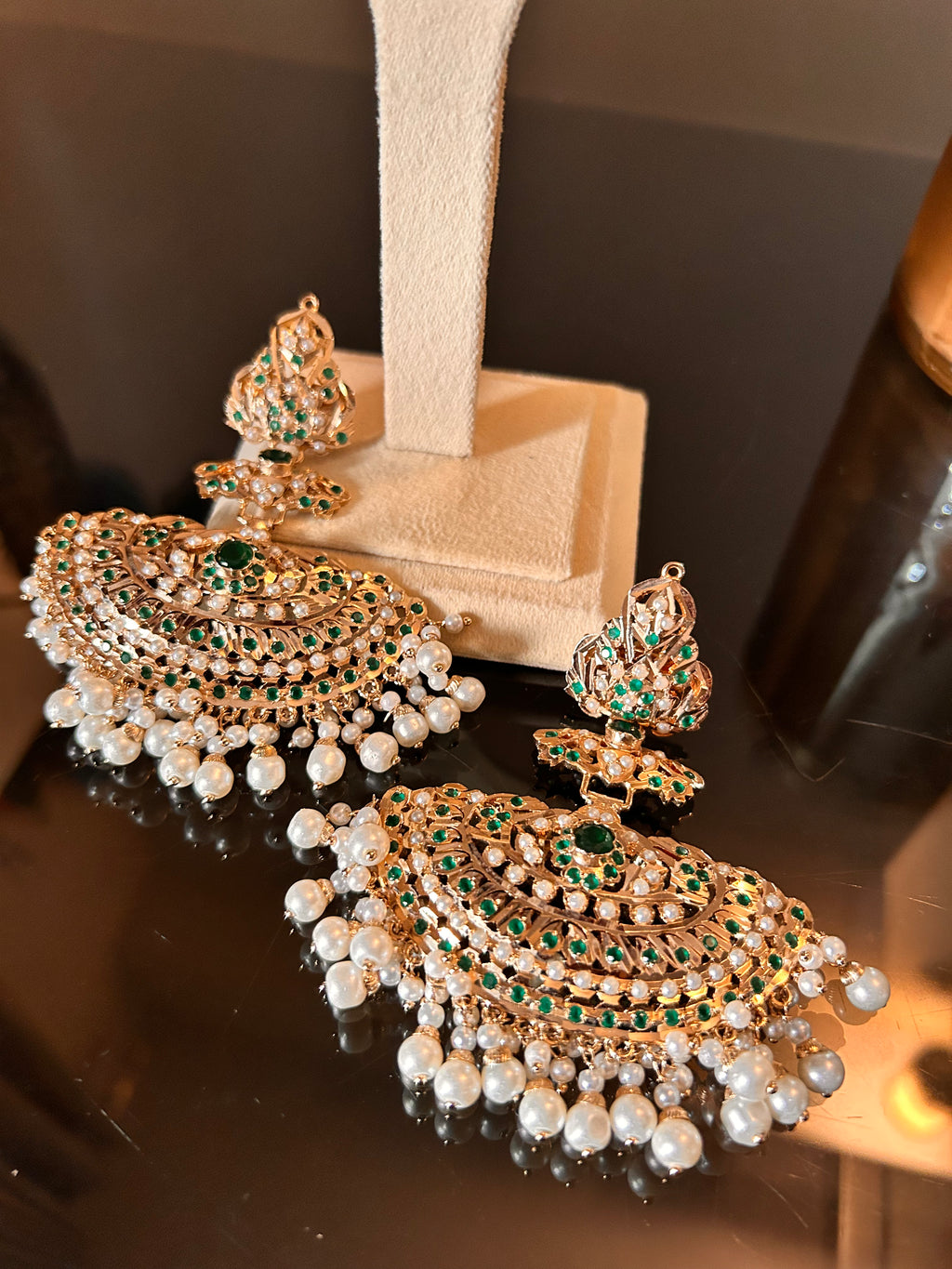 Alternate close view of the Khwahish earring pair at a cream stand base, with green stones, pink accents and pearl-like fringes.