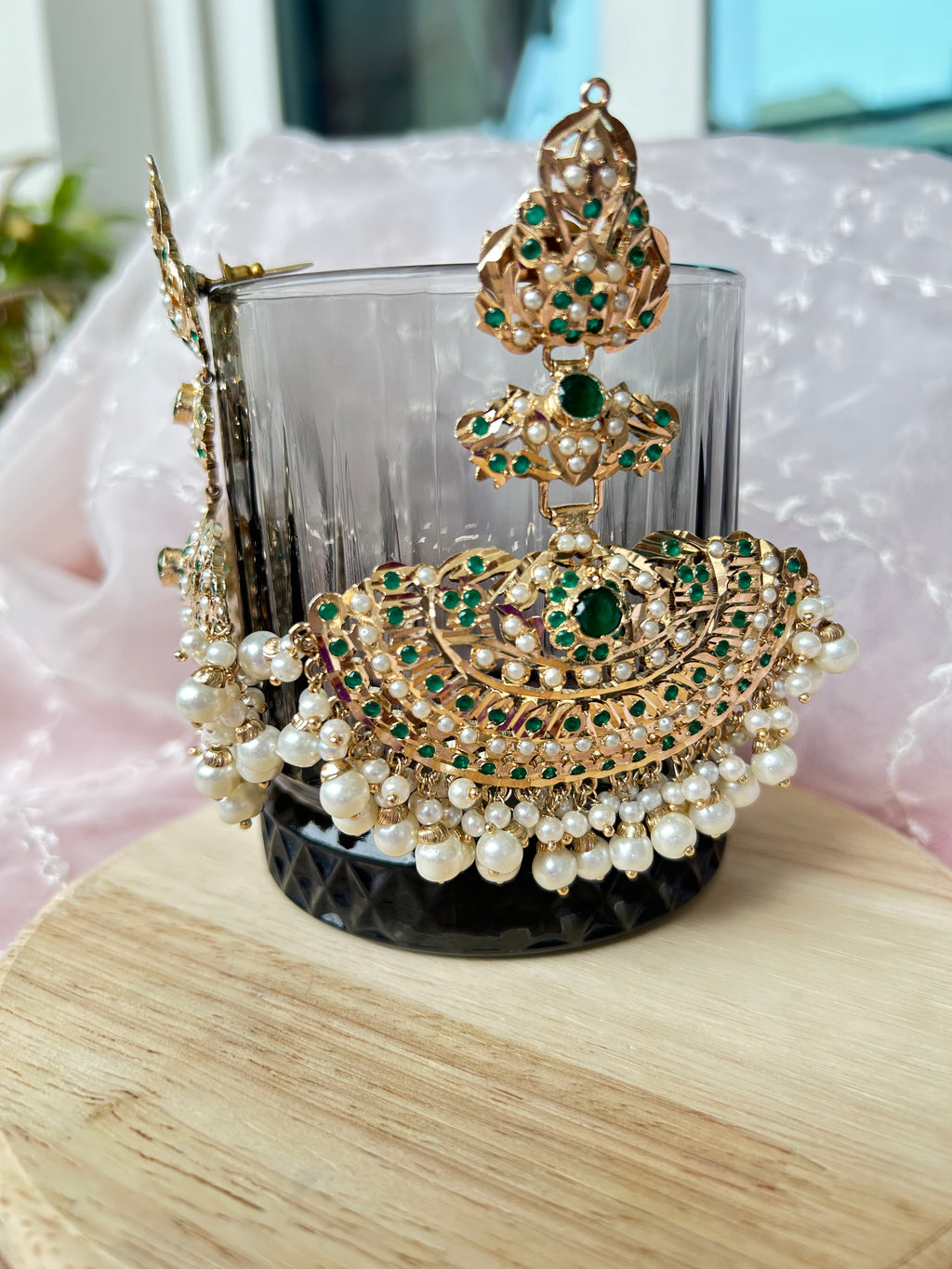 Front and side view of Khwahish green-stone earrings with pearl-like fringes, displayed on a glass.