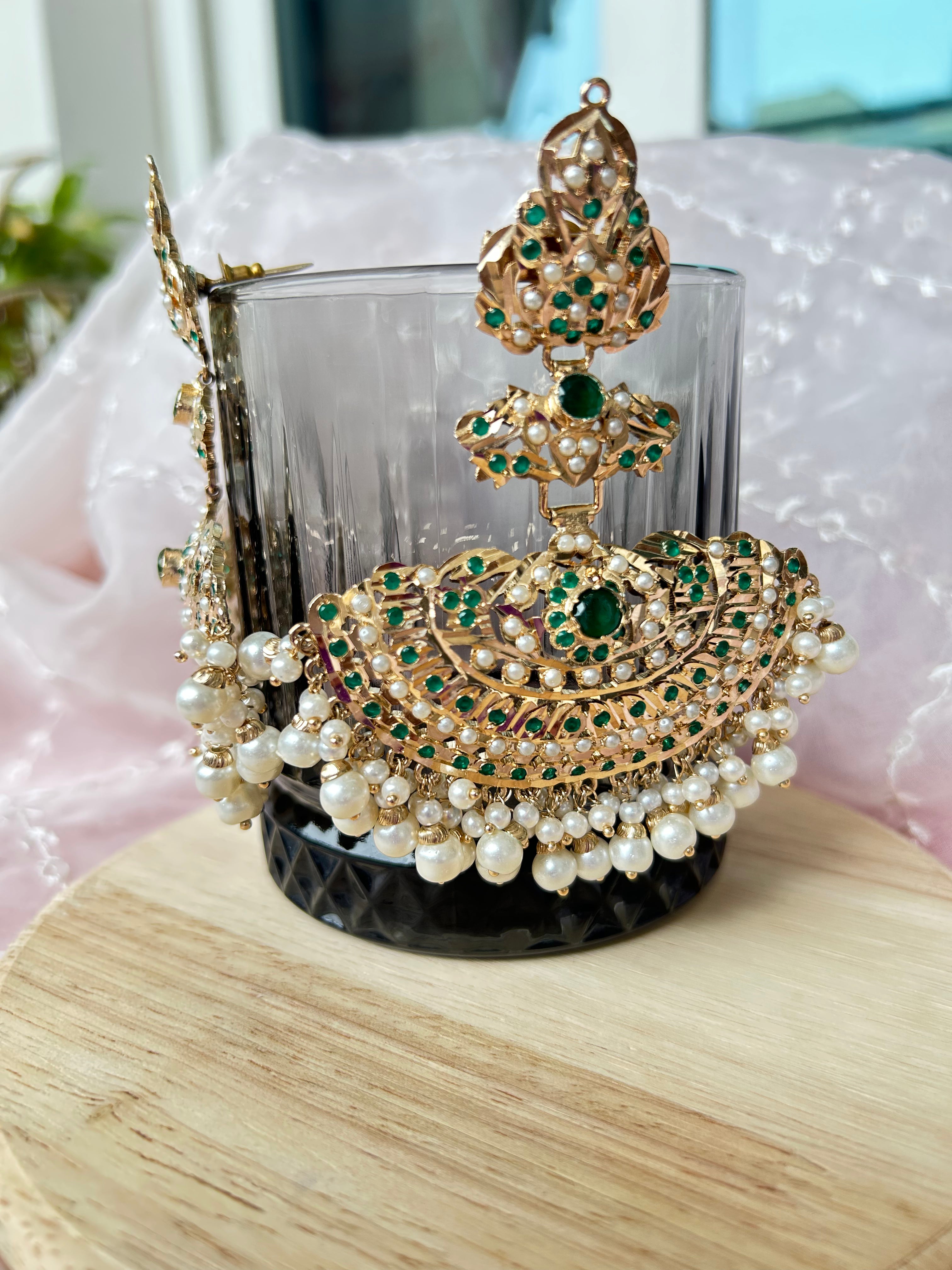 Front and side view of Khwahish green-stone earrings with pearl-like fringes, displayed on a glass.