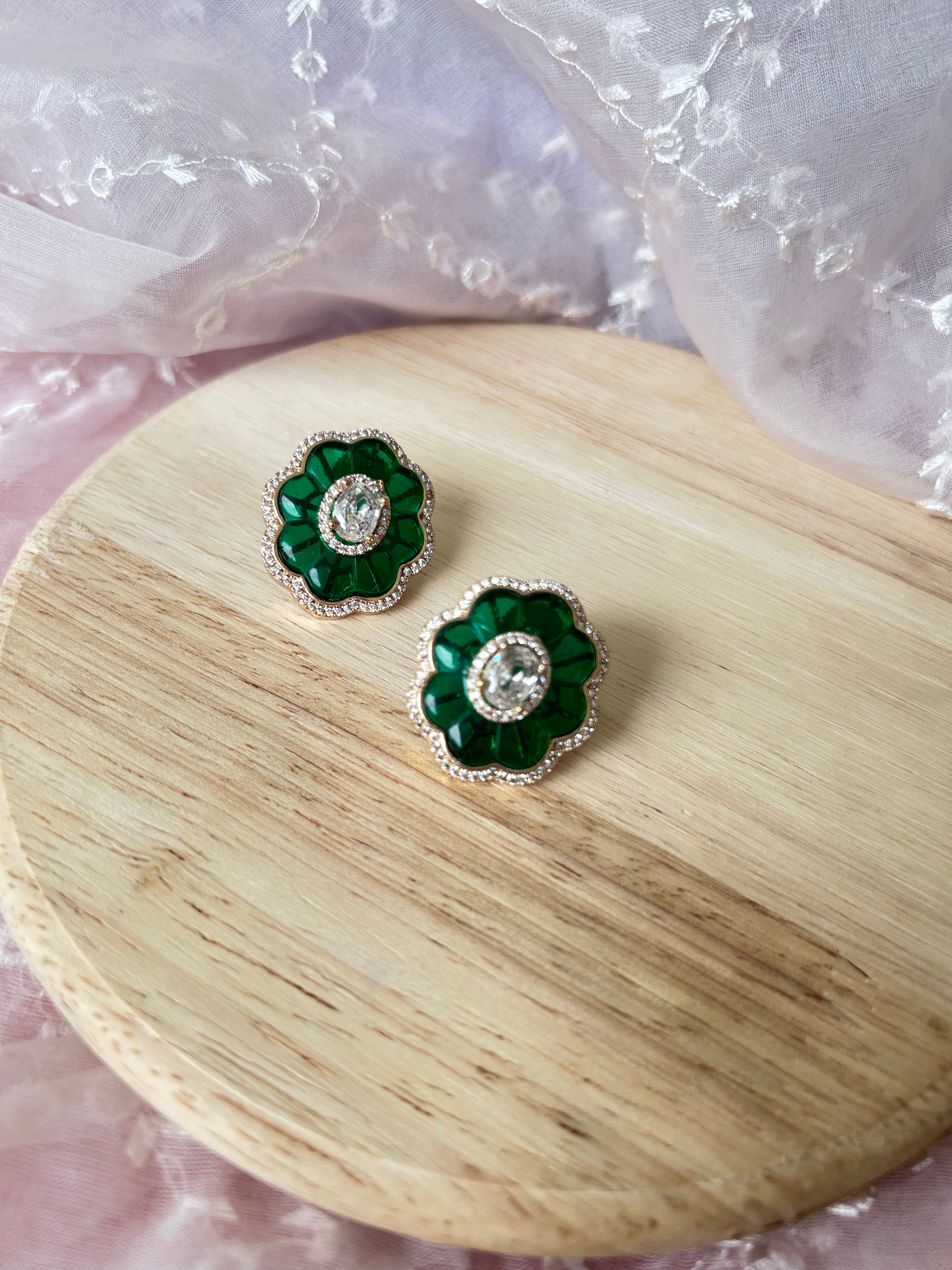 Ruh Earrings detail view showing American diamonds and green stones in brass.