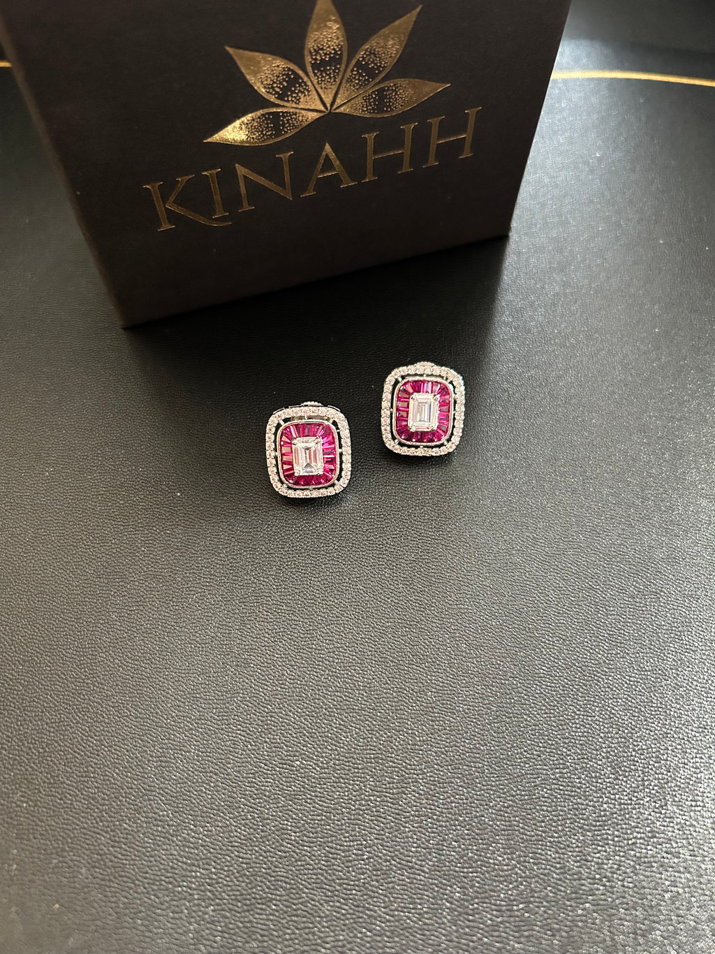 SIA Earrings detail view showing American diamonds, red stones and rhodium plating.