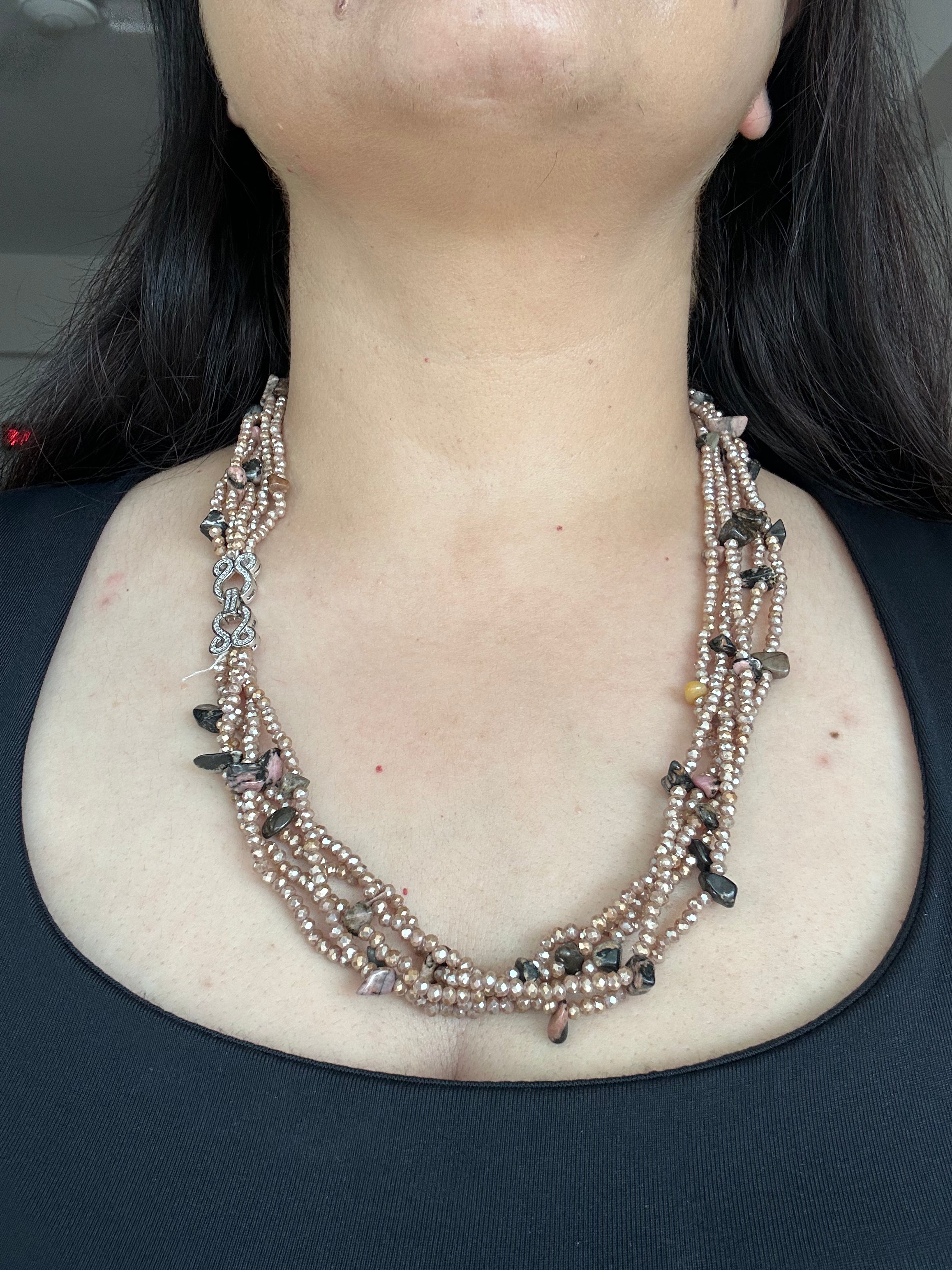 Evara Necklace in brown, worn from the front to show the layered bead strands and clear-stone linked clasp.