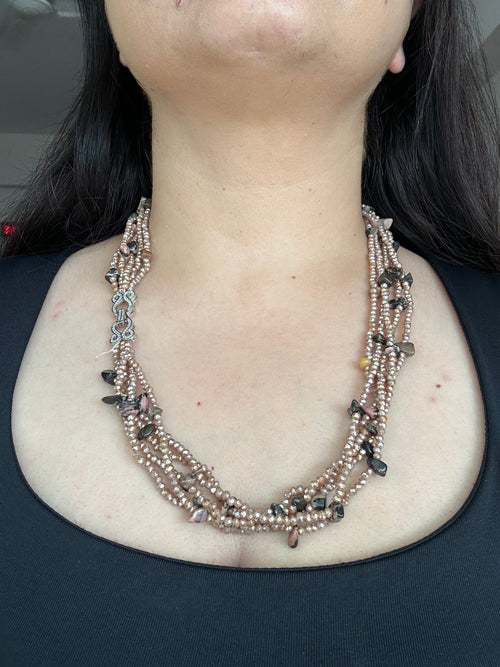 Evara Necklace in brown, worn from the front to show the layered bead strands and clear-stone linked clasp.