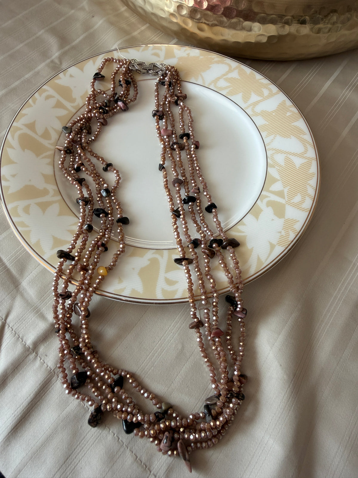 Flat lay of Evara brown multi-strand beaded necklace, showing the decorative clear-stone clasp.