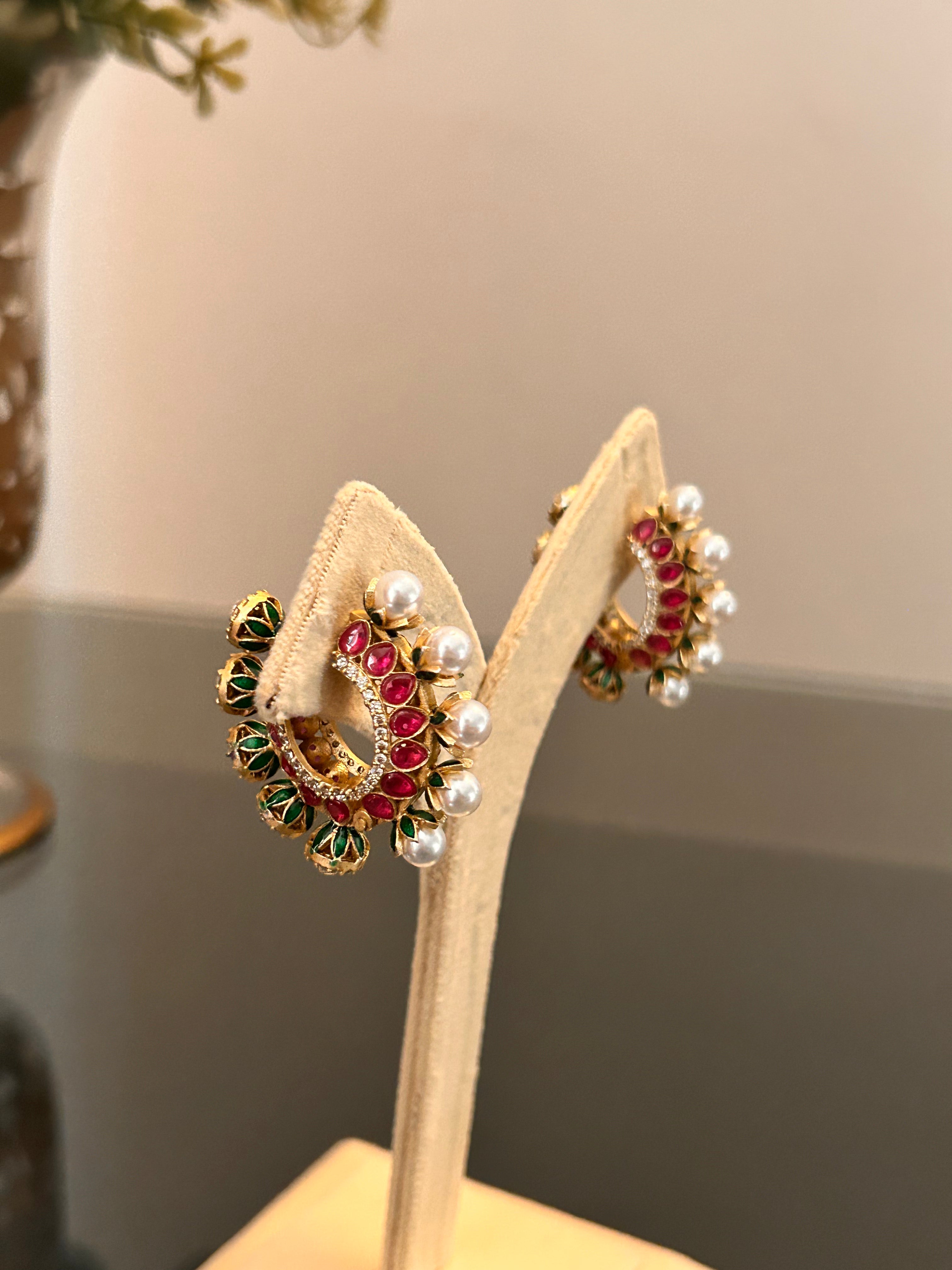 Angled stand view of Gulnaar Hoops with pink and green enamel and pearl-like drops.