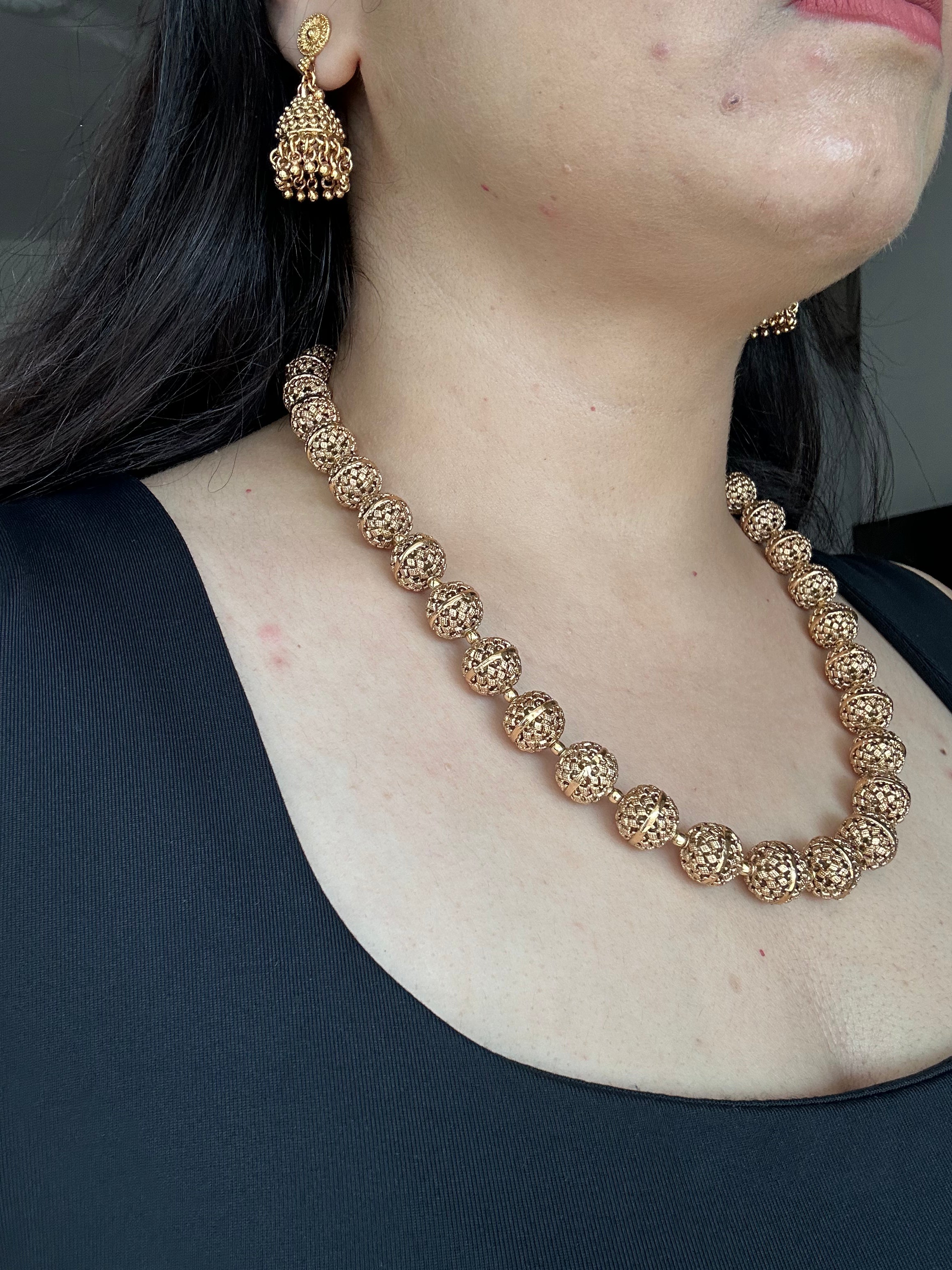 Angled worn view of Maira Mala Set, showing carved gold-tone beads and matching jhumka earrings.