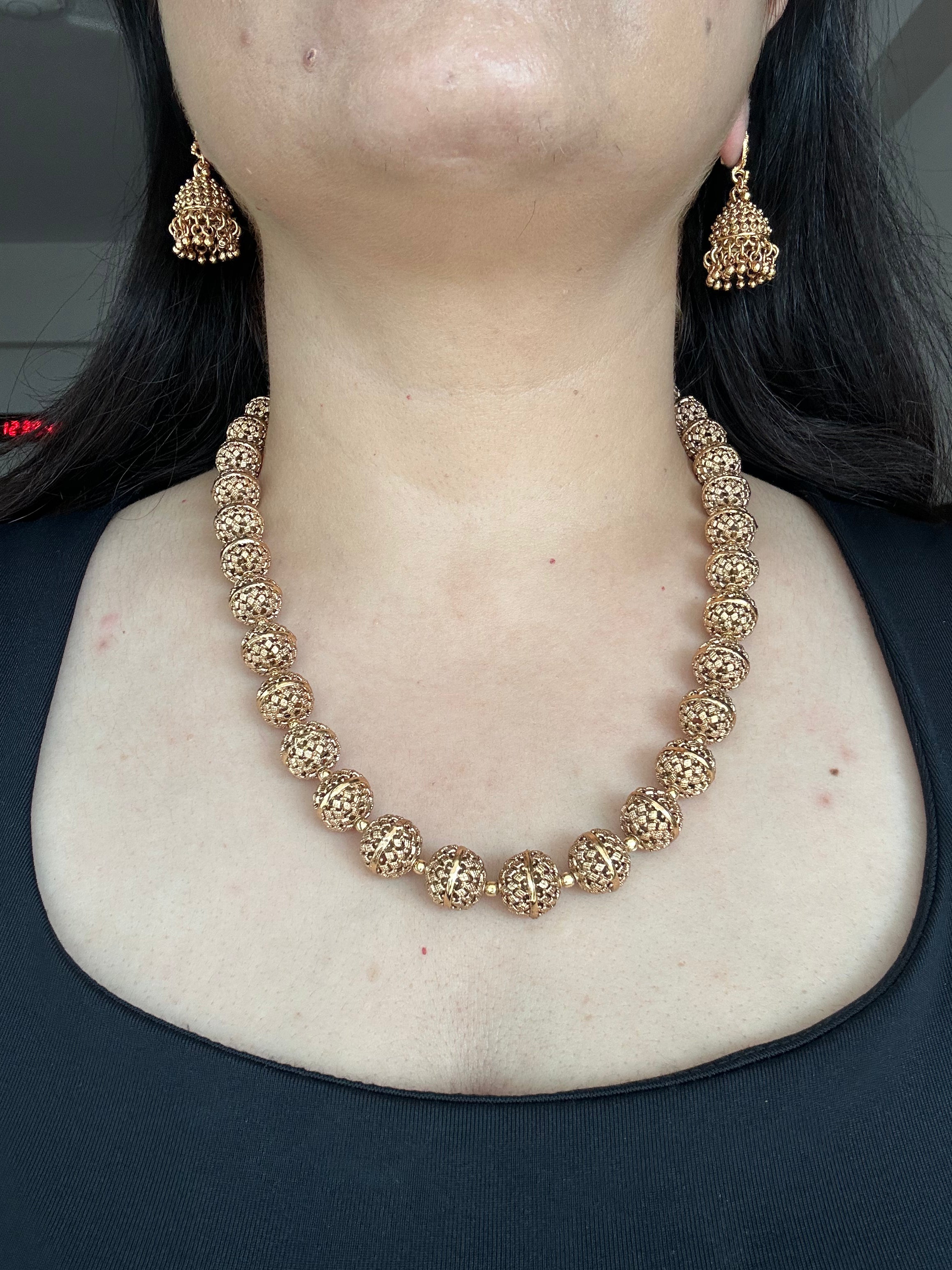 Maira Mala Set by KINAHH worn from the front, showing carved gold-tone beads and matching jhumka earrings.