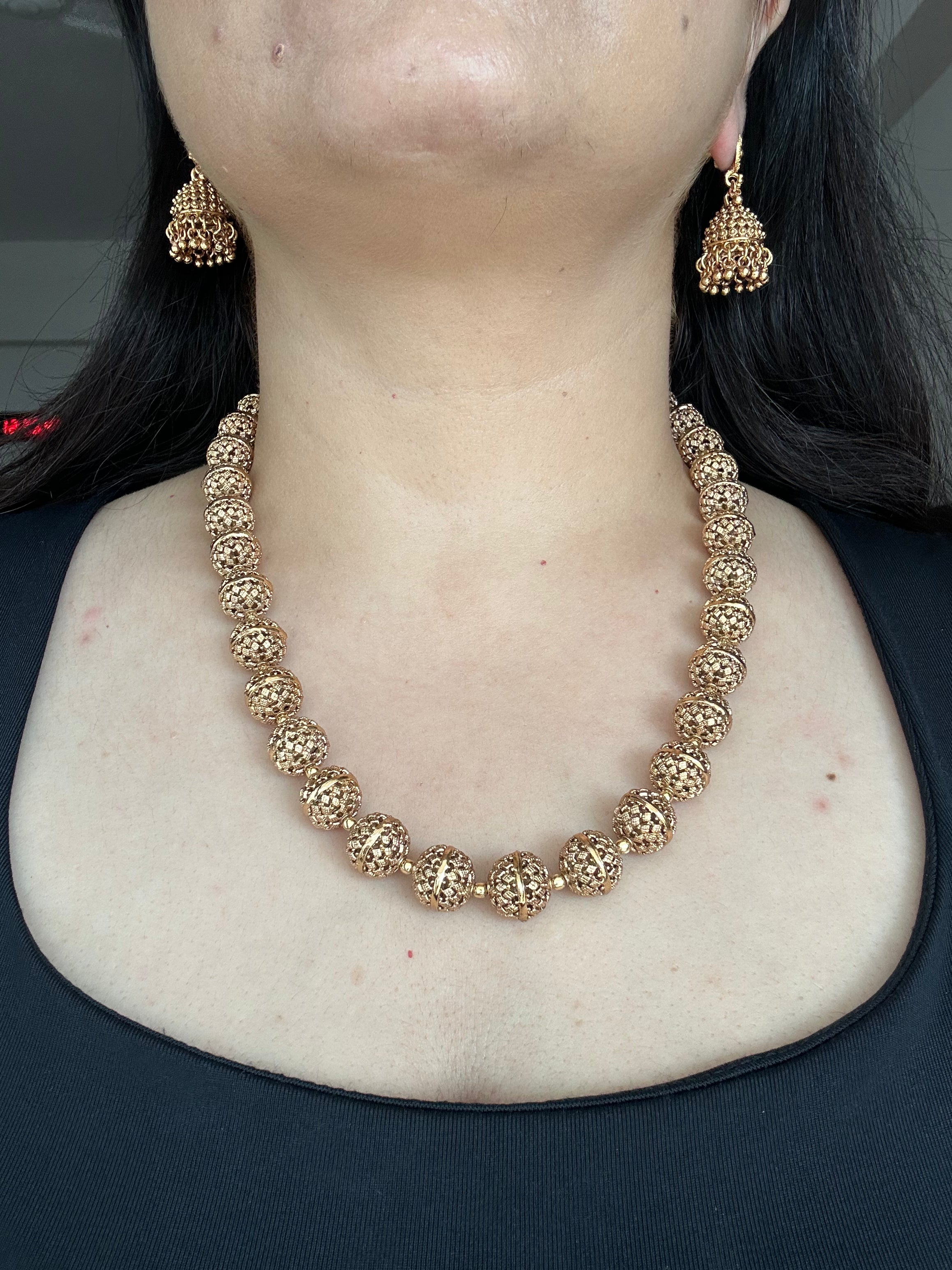 Front worn view of Maira Mala Set with its rounded carved beads and matching jhumka earrings.