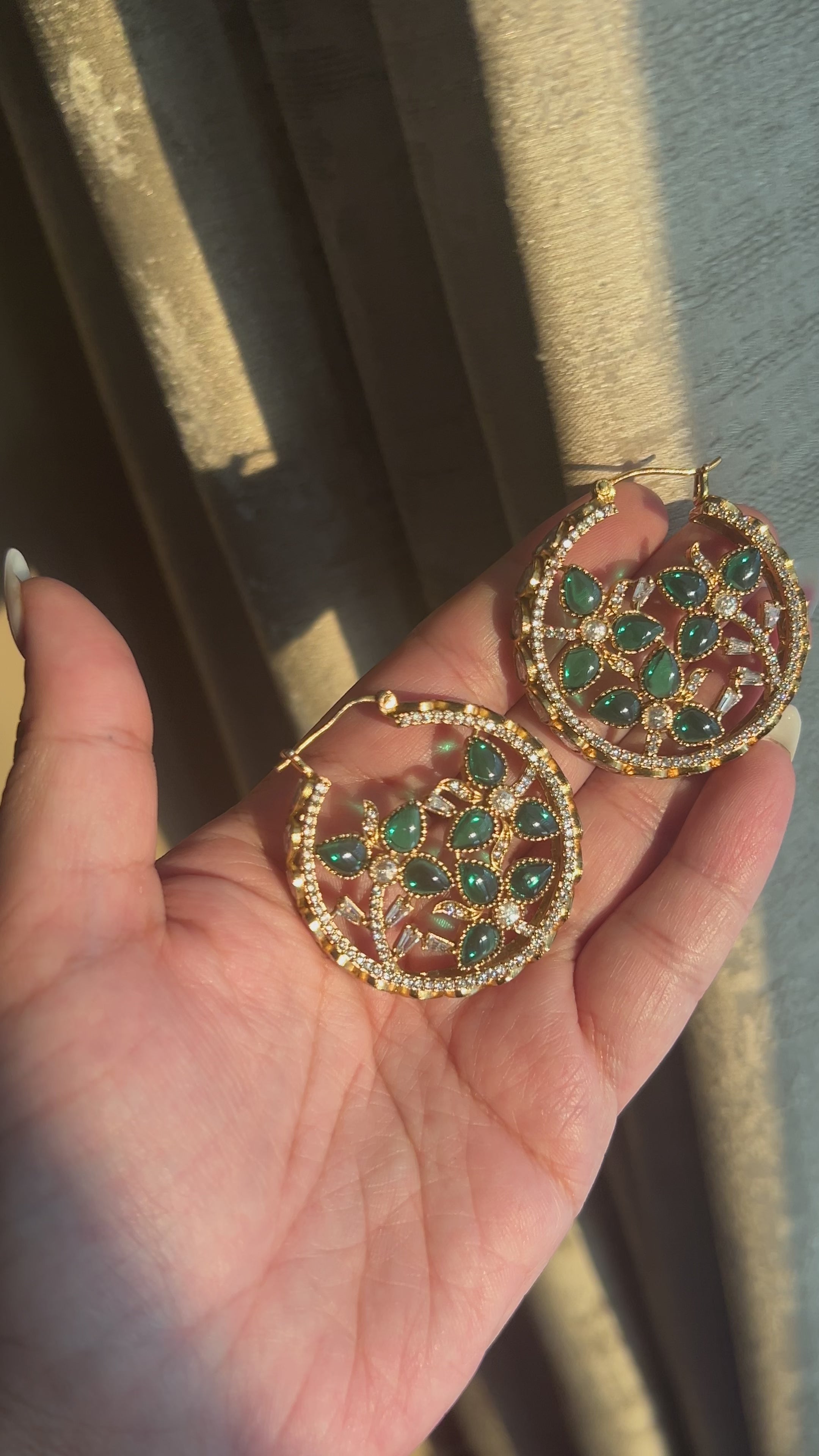 Client video of Chaand circular hoop earrings held in sunlight, showing green stones, polki detailing and movement.