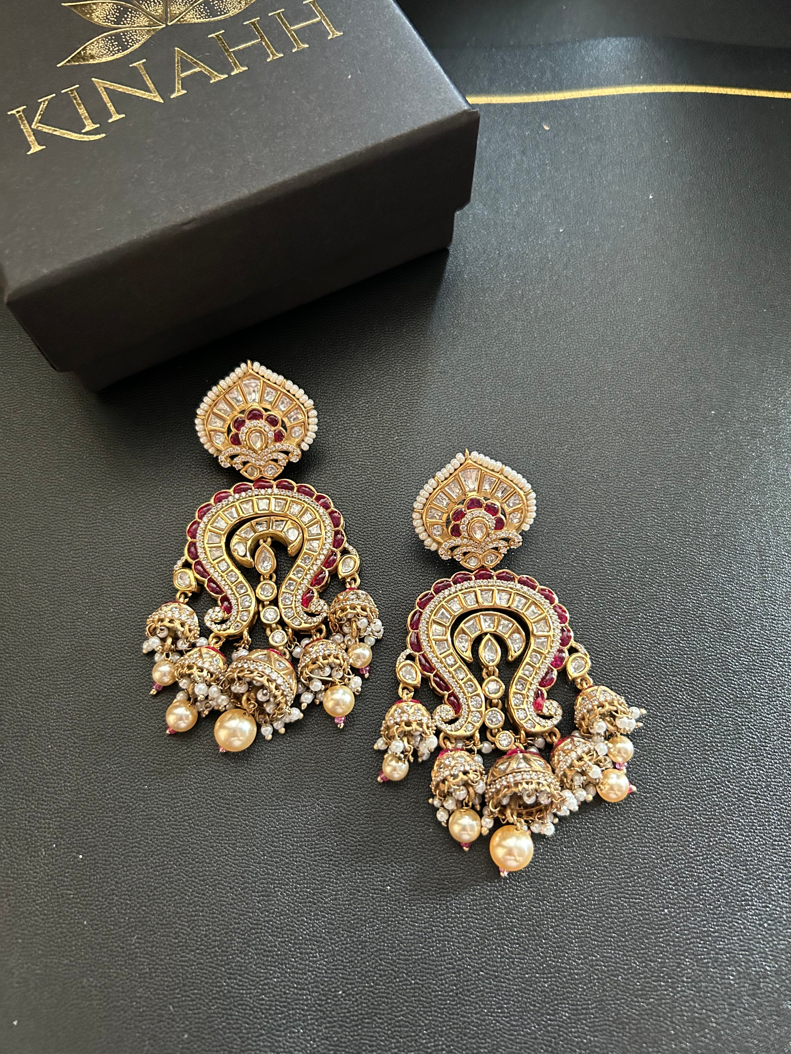 Pair of Saanjh ornate earrings on a black background beside the KINAHH jewellery box.