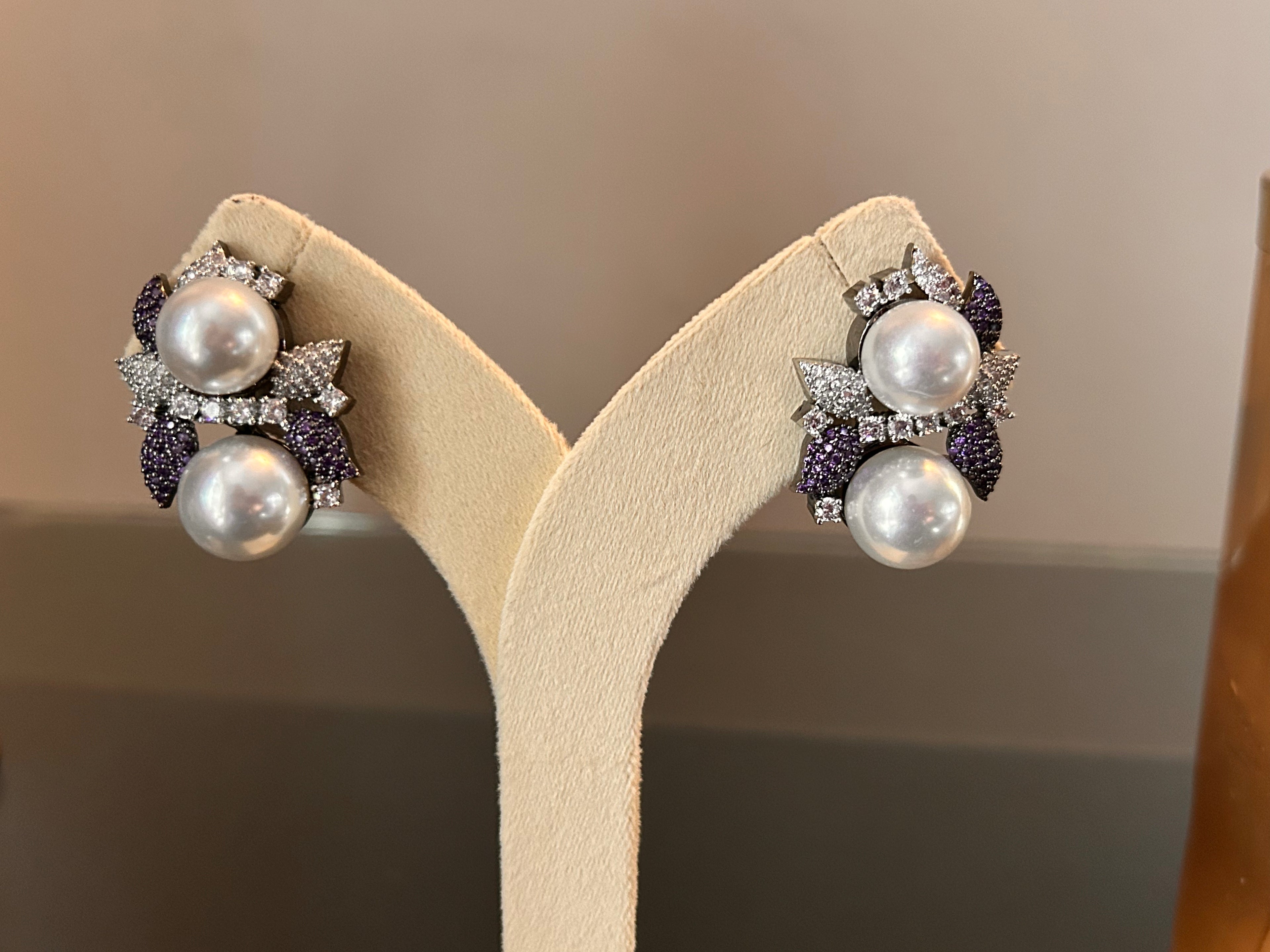 Close pair view of Sephora Earrings on a cream display stand.